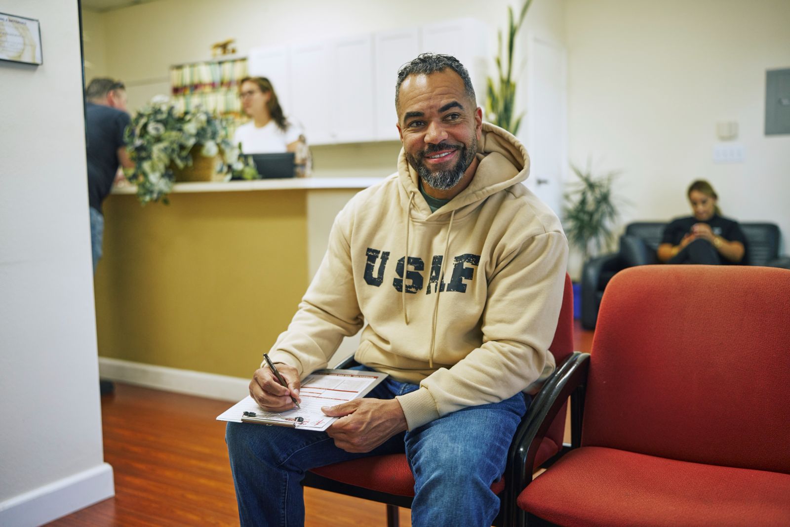 An Air Force veteran smiles while filling out paperwork in a Tampa clinic waiting room