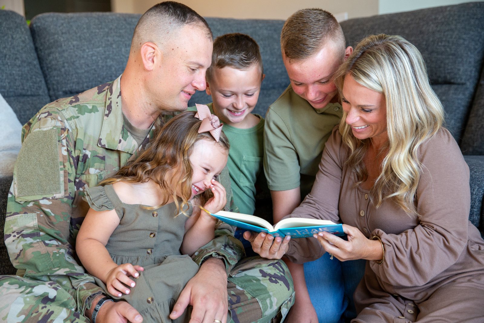 An Army family laughs together while reading on the couch