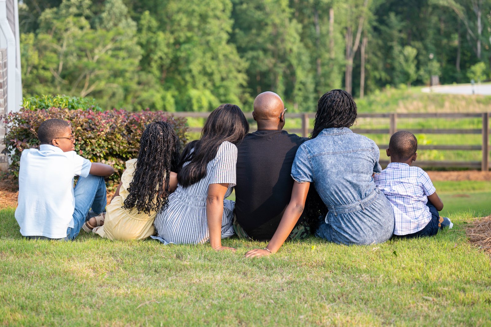 A military family sits together on the grass in their backyard