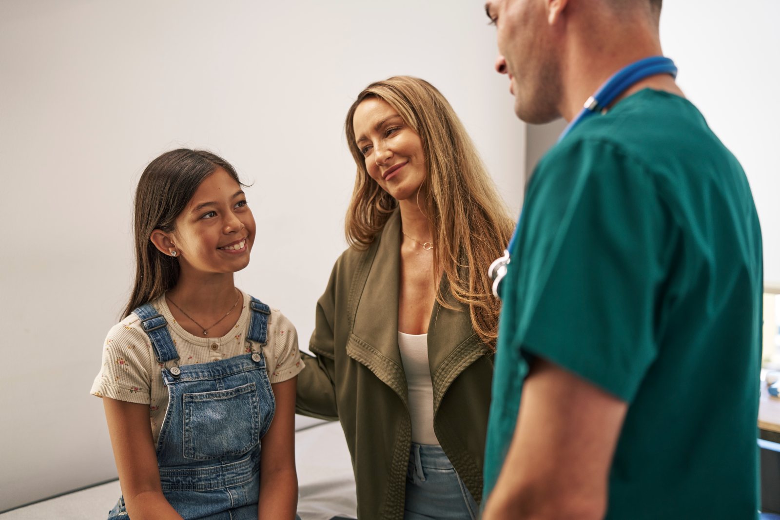 A mother and daughter talk with a nurse during a pediatric visit