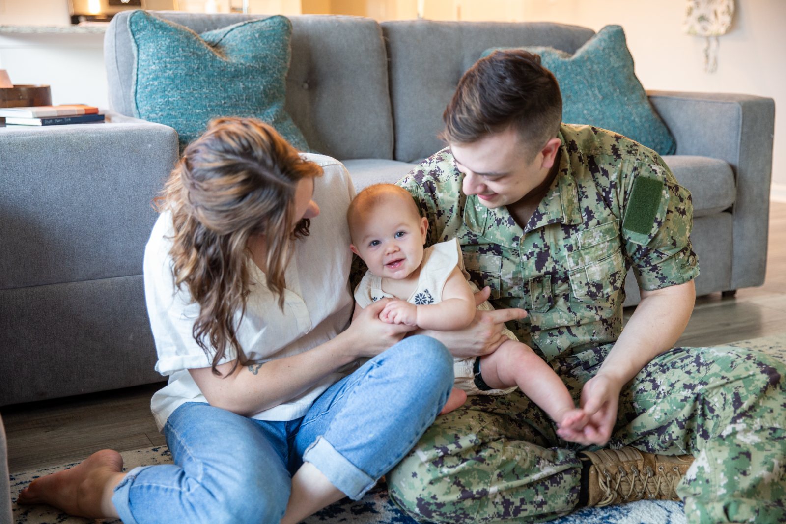 A Navy sailor and his wife play with their baby at home